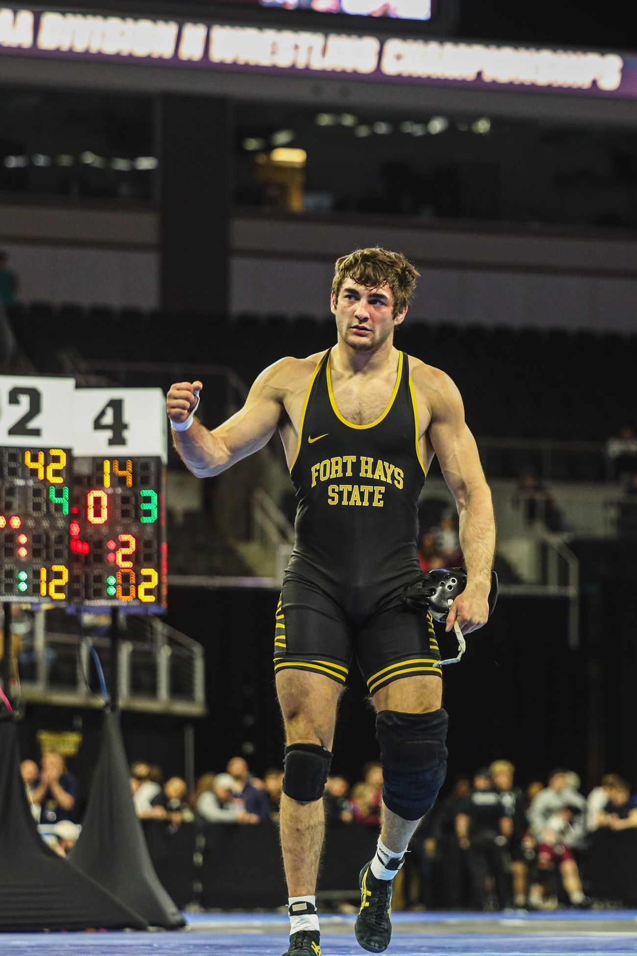 A wrestler at the NCAA Division II Championships with the scoreboard behind him