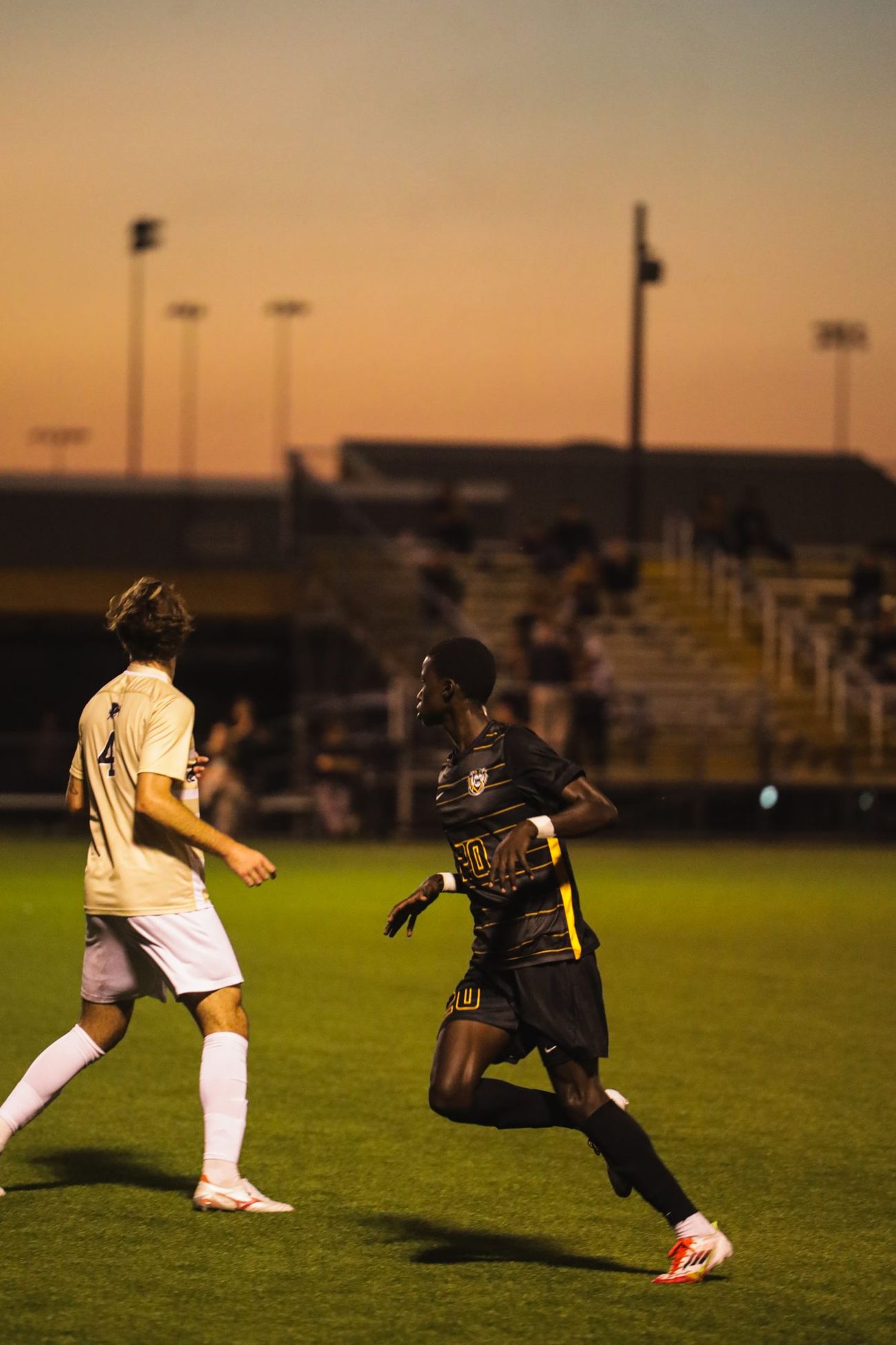 A soccer player running along the pitch at sunset